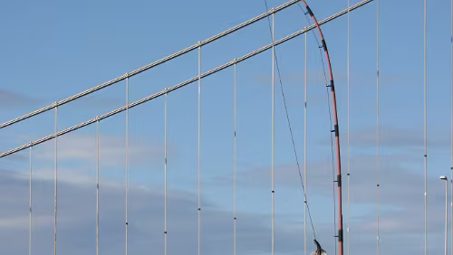 Skarsvåg – Vadsø Eine ziemlich große Angel, im Hintergrund die Tana bru. Diese hat aber leider eine traurige Geschichte: „Tana – Verdens største fiskestang – Fiskestangen ved...