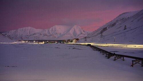 Rundgang Longyearbyen Blick vom „Vei 106“ auf Longyearbyen, links wo die schwarzen Schotterstreifen zu sehen sind, fließt im Sommer der „Longyearelva“. Rechts die oberirdischen Rohre...