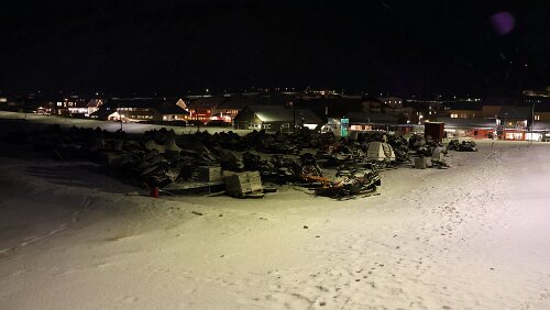 Longyearbyen Im Vordergrund ein Schneescooter-Parkplatz. Rechts der Kindergarten „Kullungen barnehage“.