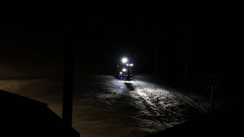 Longyearbyen Auf der Skipiste fährt ein Bagger ganz langsam herab, es sieht aus als ob er jeden Moment nach vorne kippen würde.