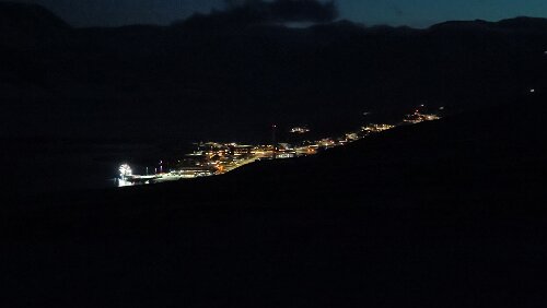 Seed Vault Hike - From Seed to Summit Links ein Stück des Hafenbereichs. In der Mitte kann man den hohen Schornstein des Kohlekraftwerkes mit seinen roten Lichtern erkennen.