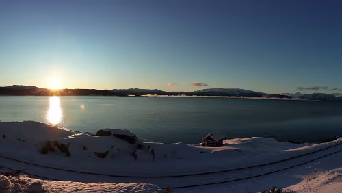 Bodø – Saltfjellet – Mosjøen Sonnenaufgang am „ Skjerstadfjorden “. Im Vordergrund die Eisenbahnlinie zwischen Fauske und Bodø. Panorama .