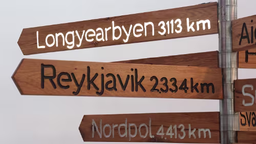 Wegweiser aus Stahlrohr mit Schildern aus Holz Longyearbyen strahlt von innen.